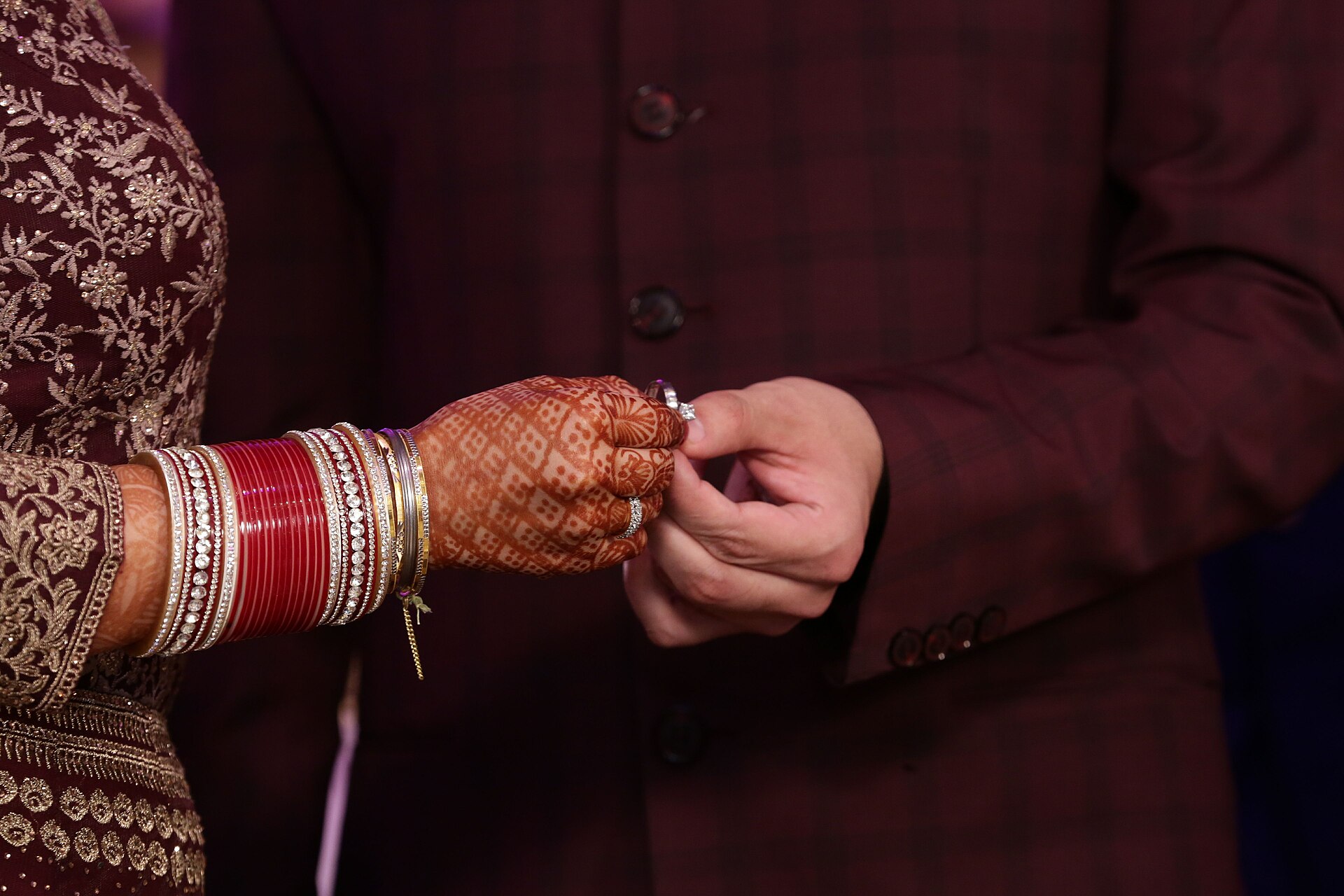 A ring being placed on a mehndi-covered hand